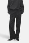 Pantalon gris de MANGO, avec une coupe droite et des plis verticaux, associé à un sweat-shirt foncé.
