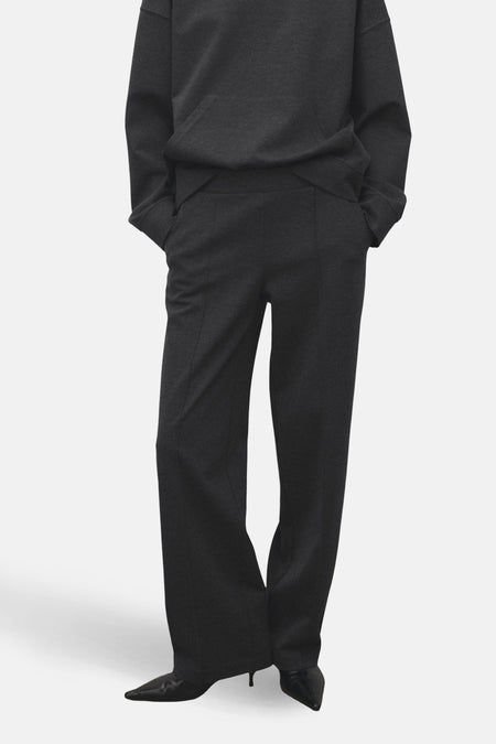Pantalon gris de MANGO, avec une coupe droite et des plis verticaux, associé à un sweat-shirt foncé.
