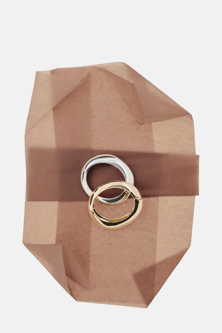 Bracelets dorés et argentés de MANGO présentés sur un papier d'emballage marron.