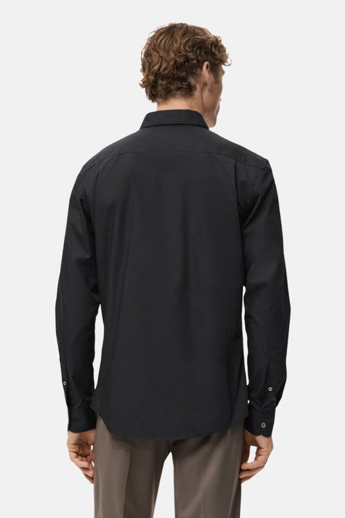 Chemise à manches longues noire de MANGO, vue de dos, avec pantalon marron.
