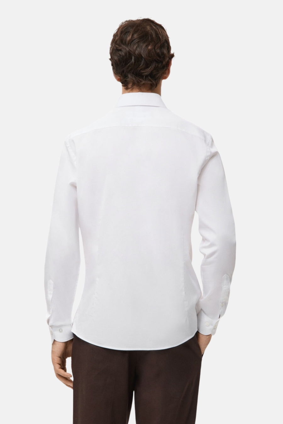 Chemise blanche à manches longues de MANGO, vue de dos, portée avec un pantalon marron.
