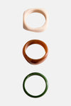 Bracelets multicolores de MANGO, avec un bracelet carré blanc, un bracelet marron brillant et un bracelet vert uni.
