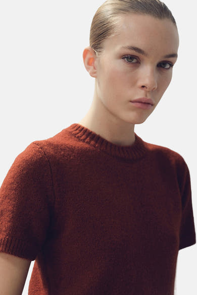 Pull ras du cou brun de MANGO, en maille fine, porté par une femme regardant vers l'objectif.
