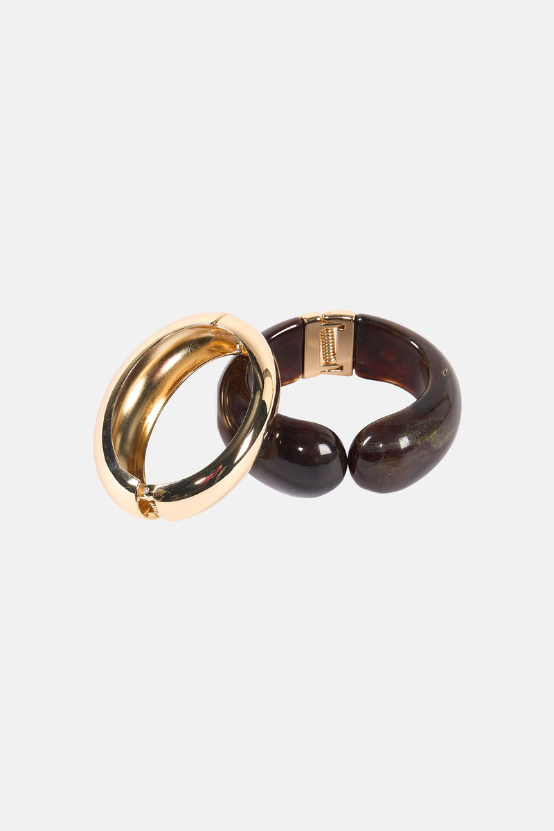 Gouden stijve armband van Mango, met een contrasterende bruine hoorn-effect armband, gelaagd.
