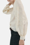Ecru blouse met lange mouwen van MANGO, met bloemenborduursels en gedragen met een donkere jeans en een bruine riem.