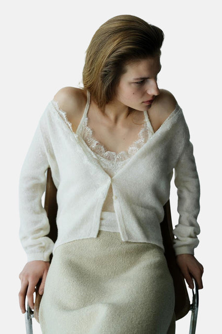 Gilet écru de MANGO avec bordure en dentelle, porté sur un caraco et une jupe coordonnés.