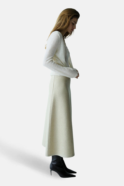 Ecru gilet van MANGO, gedragen met een lange beige rok en zwarte naaldhak laarsjes.
