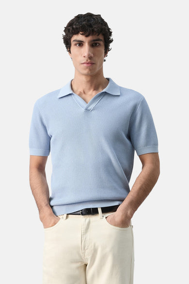 Blauwe polo met korte mouwen van MANGO, wafelstructuur detail, gedragen met een lichtbeige broek, achtergezicht.