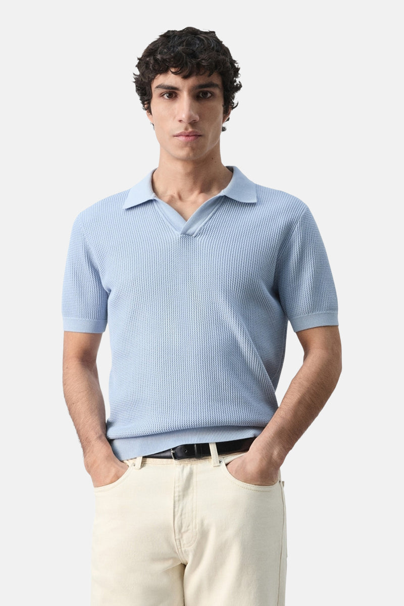 Blauwe polo met korte mouwen van MANGO, wafelstructuur detail, gedragen met een lichtbeige broek, achtergezicht.
