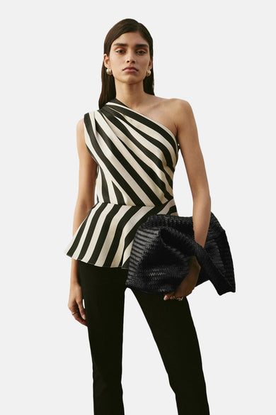 Blouse multicolore sans manches de MANGO, à rayures, portée avec un pantalon noir et un sac texturé.