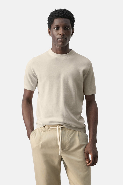 T-shirt beige à manches courtes de MANGO, porté avec un pantalon beige à cordon.