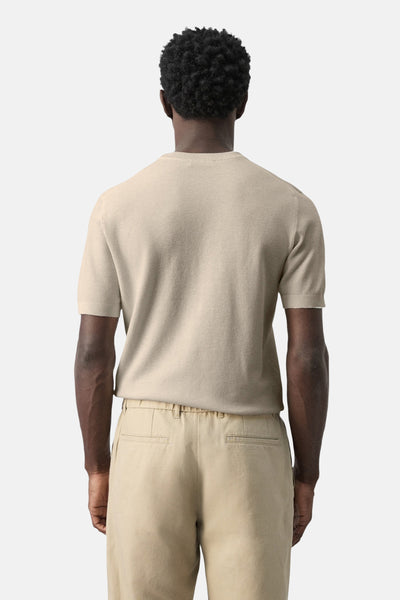 T-shirt beige à manches courtes de MANGO, porté avec un pantalon beige assorti, vue de dos.