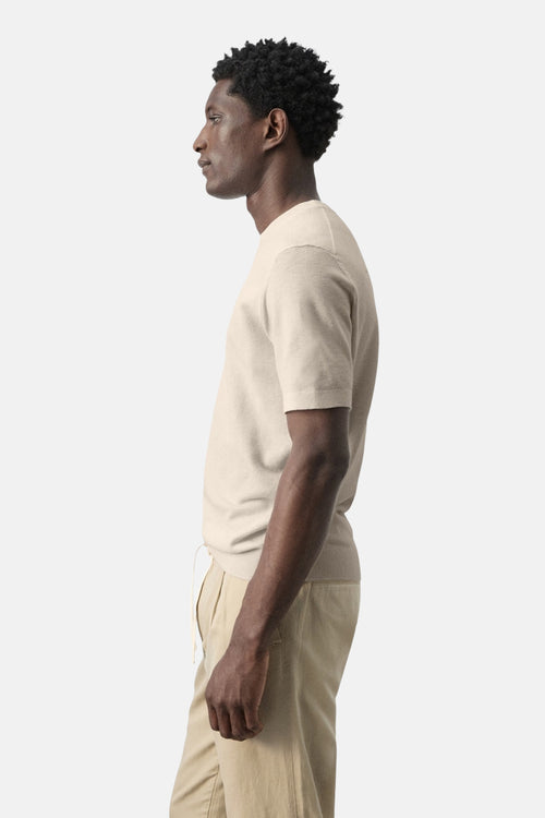 T-shirt beige à manches courtes de MANGO, porté avec un pantalon clair, en vue de profil.