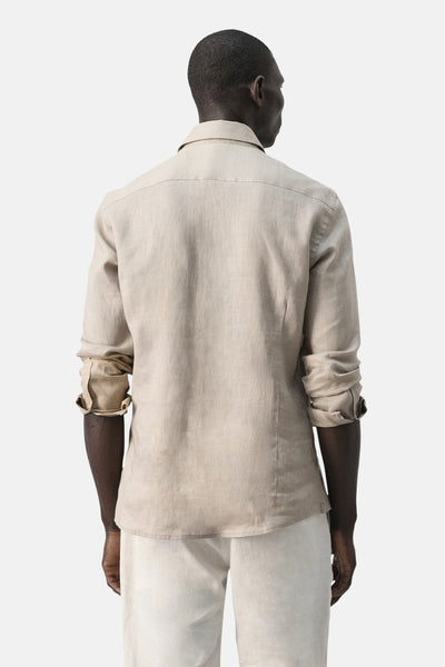 Chemise beige à manches longues de MANGO, vue de dos, portée avec un pantalon clair.