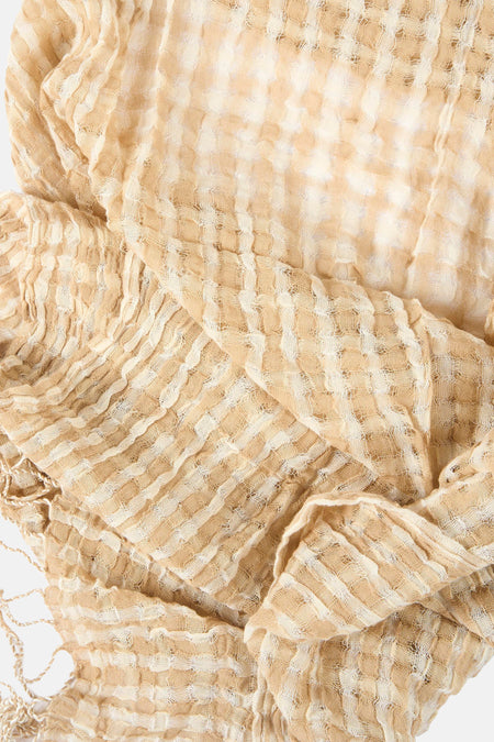 Foulard écru de MANGO, motif quadrillé gaufré, avec des franges décoratives sur un fond clair.
