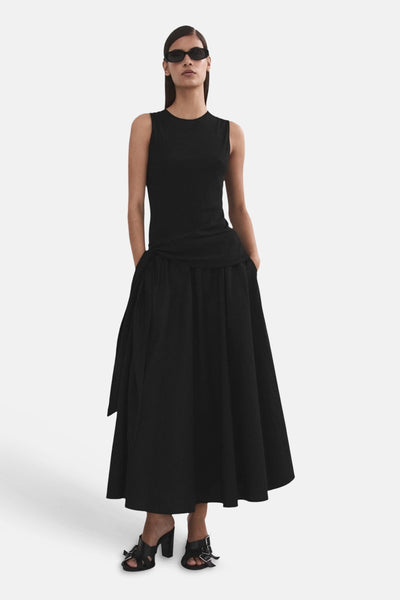 Jupe longue noire de MANGO, avec détail noué à la taille et poches, portée avec un haut noir.
