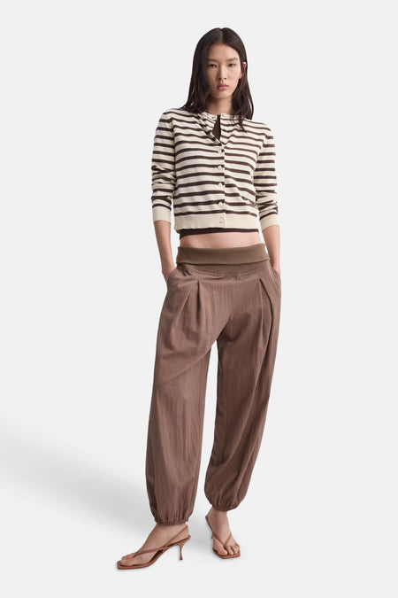Gilet multicolore de MANGO, rayé écru et marron, coupé court, porté avec un pantalon ample et des sandales à talons.