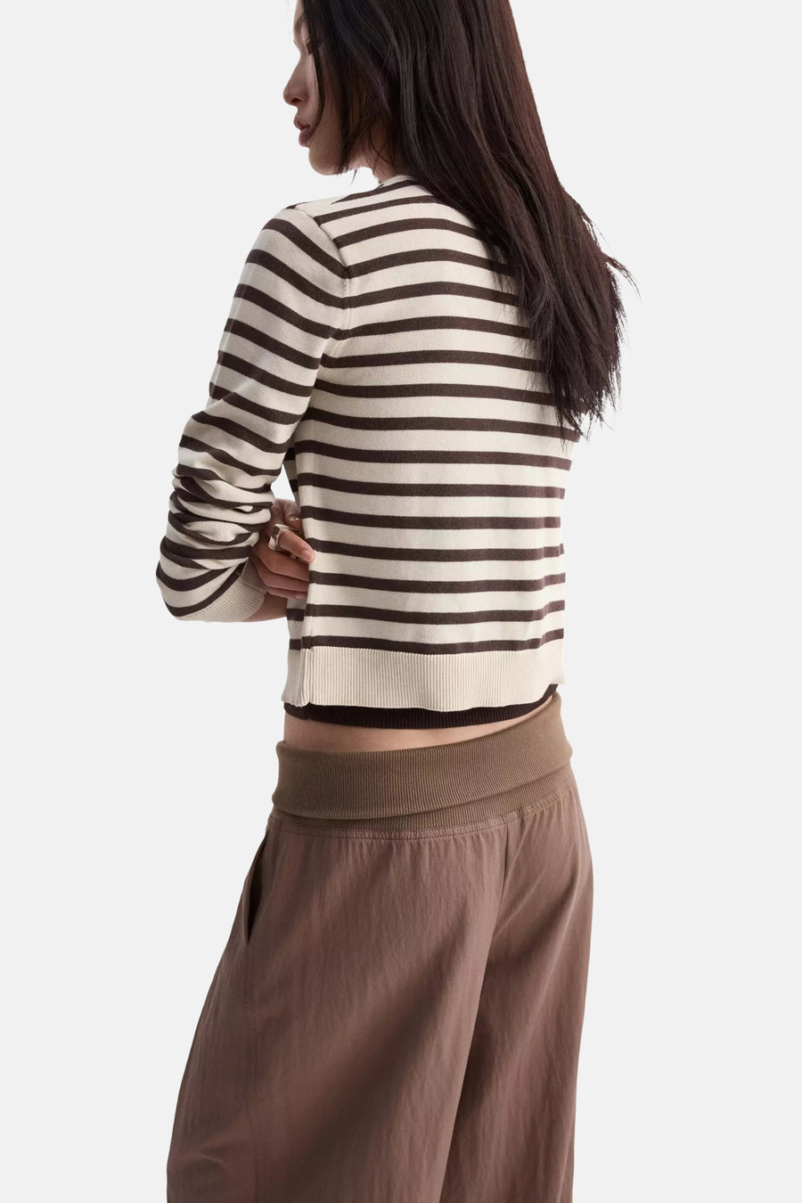 Gilet rayé crème et marron de MANGO, coupé court, porté de dos avec un pantalon marron.