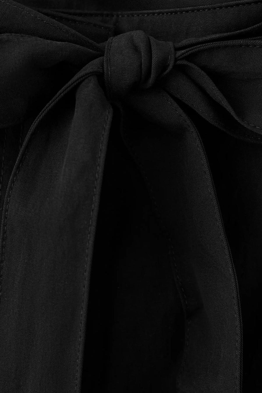 Zwarte broek van MANGO met stoffen strik, zichtbare naden en textuur, close-up.