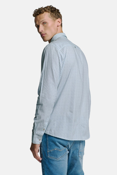 Chemise à manches longues bleue de NO EXCESS, avec un motif imprimé, portée avec un jean.