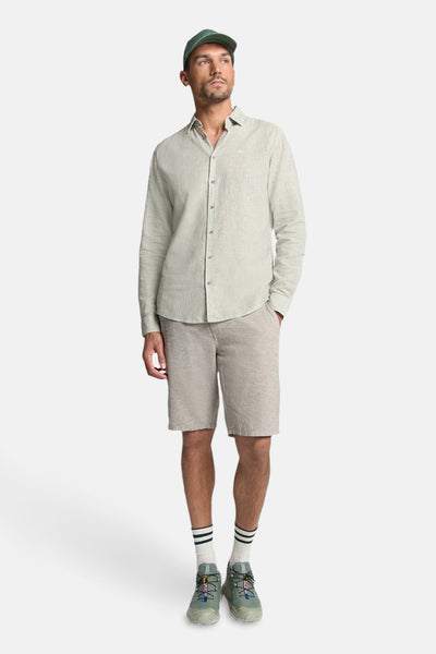Chemise à manches longues verte de NO EXCESS, portée avec un casquette et des shorts beiges.