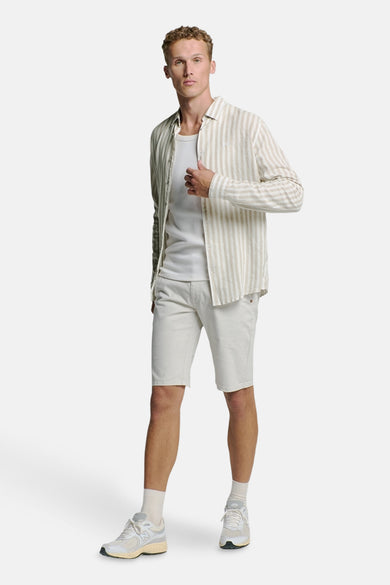 Chemise beige à manches longues de NO EXCESS, avec rayures verticales, portée sur un t-shirt blanc et un short beige.