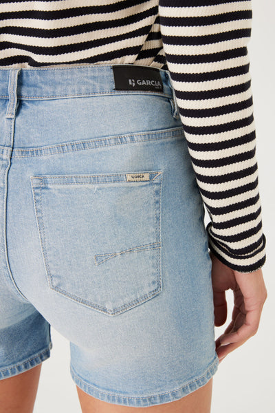 Short en jean bleu de GARCIA, avec poche arrière et détail de couture, porté avec un haut rayé noir et blanc.
