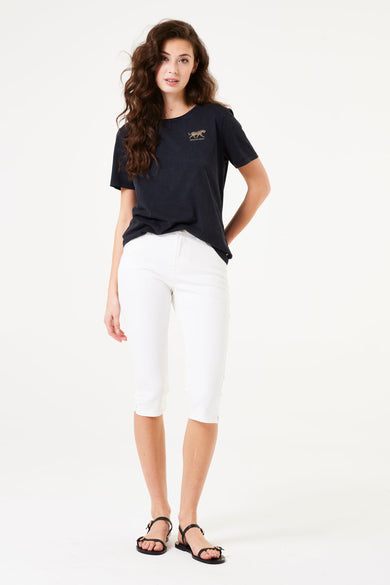 Bermuda chino blanc de GARCIA, porté avec un t-shirt noir à motif tigre et des sandales noires à lanières.
