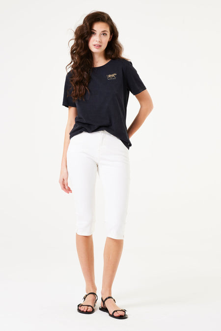 Bermuda chino blanc de GARCIA, porté avec un t-shirt noir à motif tigre et des sandales noires à lanières.