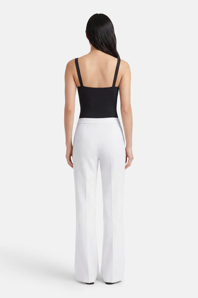 Pantalon de costume blanc, de MANGO, porté avec un haut noir à bretelles fines.