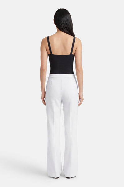 Pantalon de costume blanc, de MANGO, porté avec un haut noir à bretelles fines.