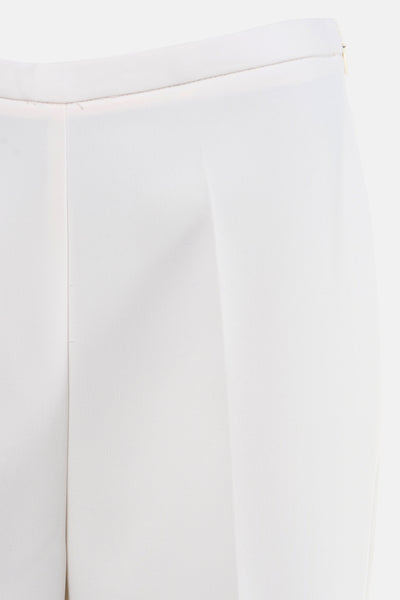 Pantalon de costume beige de MANGO, avec pli vertical, et détails de confection visibles.