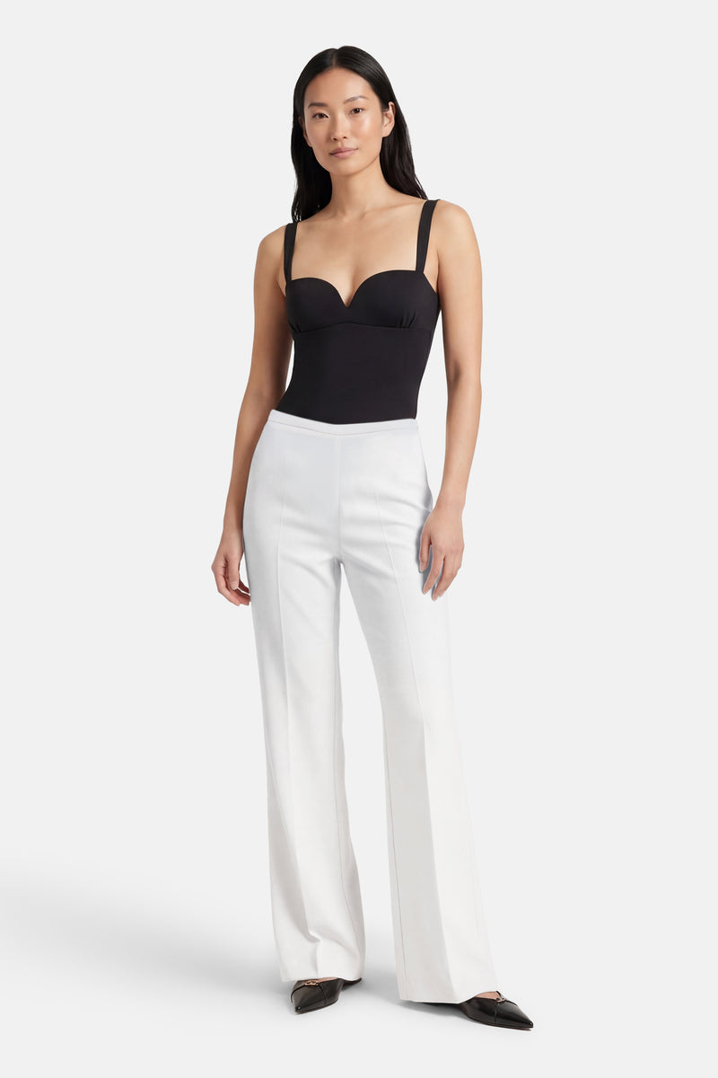 Pantalon de costume beige de MANGO, porté avec un haut noir et des chaussures plates.
