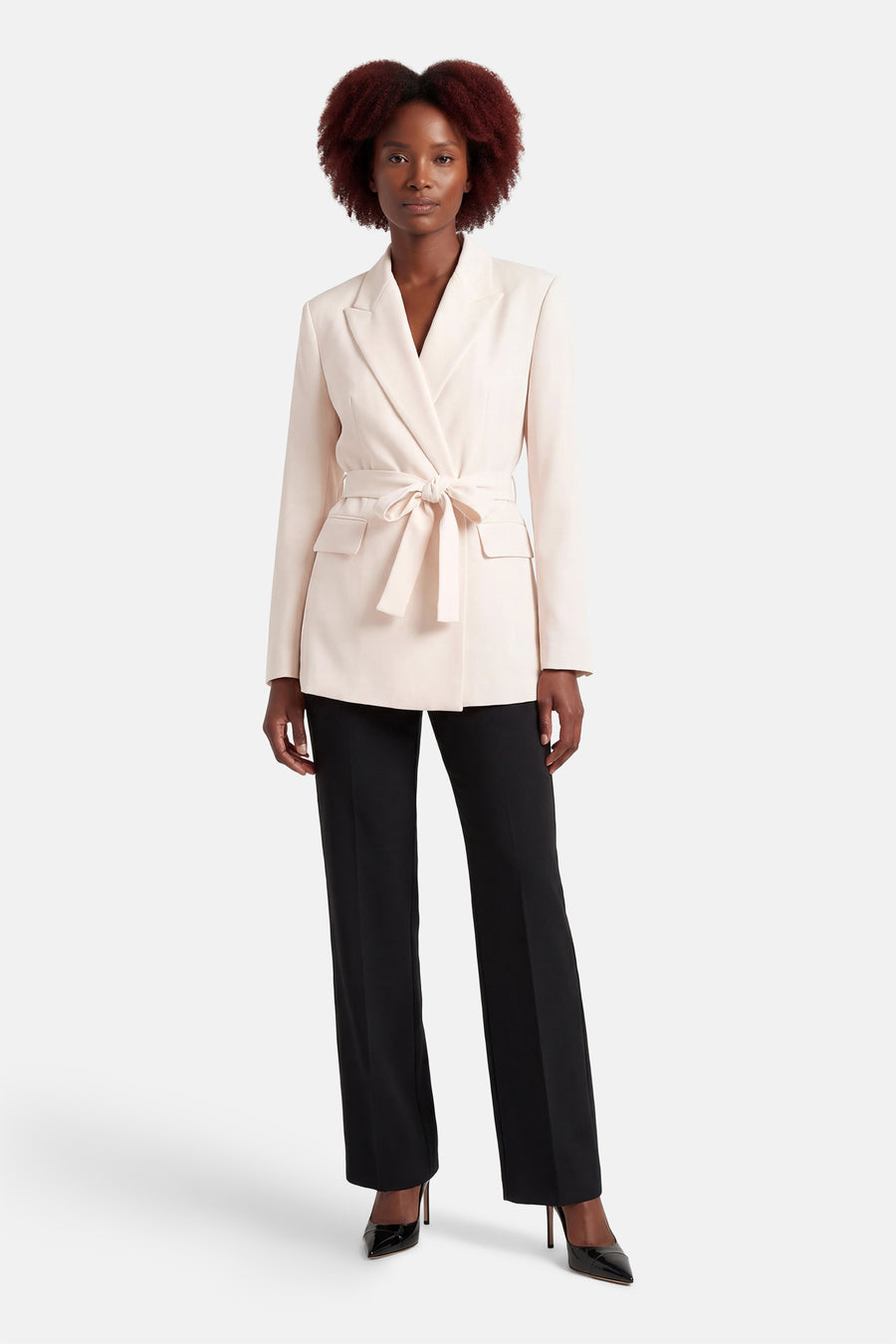 Blazer écru de MANGO avec ceinture à nouer, poches à rabat et pantalon noir.