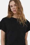 Zwarte top van MANGO, gedragen met een witte broek, van achteren zichtbaar.