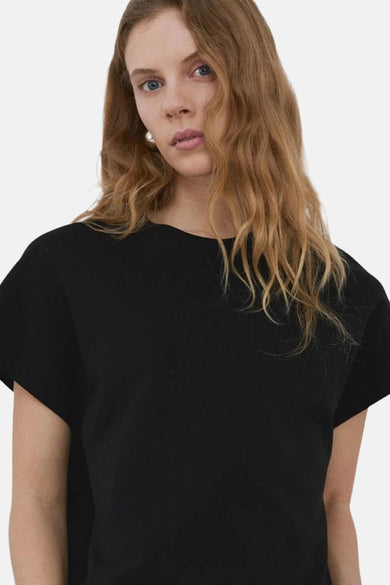 Zwarte top van MANGO, gedragen met een witte broek, van achteren zichtbaar.