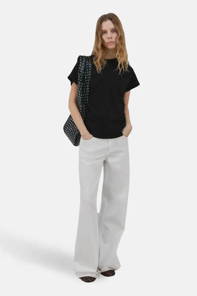 Zwarte top van MANGO, gedragen met een wijde witte jeans en een gestippelde schoudertas.