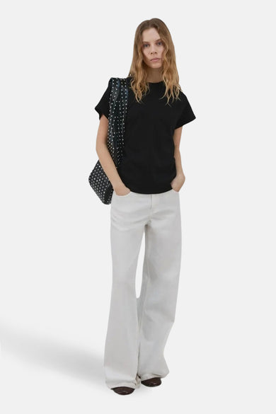 Zwarte top van MANGO, gedragen met een wijde witte jeans en een gestippelde schoudertas.