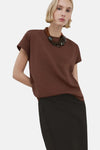 Bruin top van MANGO, gedragen met een zwarte rok met hoge taille, van achteren gezien.
