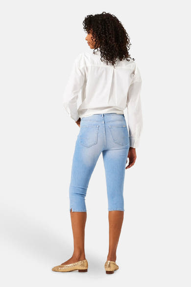 Jean denim bleu clair de GARCIA, porté avec une chemise blanche à manches longues et des chaussures dorées.