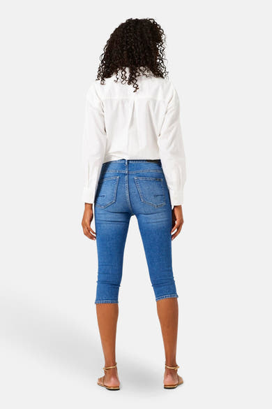 Jean bleu denim par GARCIA, vue de dos, porté avec une chemise blanche et des sandales dorées.