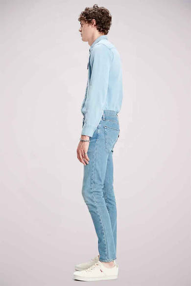 Lichtblauwe skinny jeans van Levi's, gedragen met een bijpassend denim overhemd en witte sneakers.