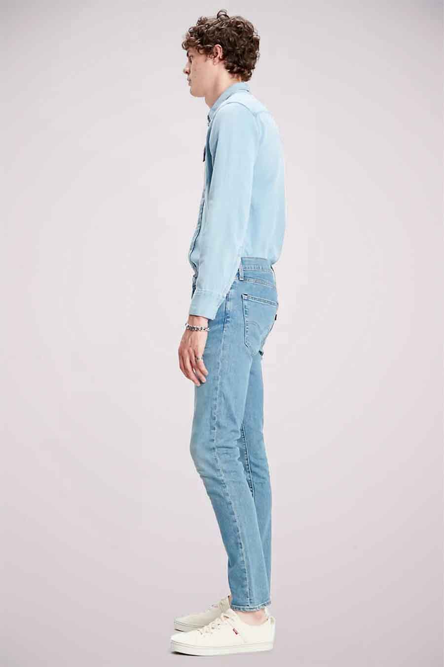 Lichtblauwe skinny jeans van Levi's, gedragen met een bijpassend denim overhemd en witte sneakers.