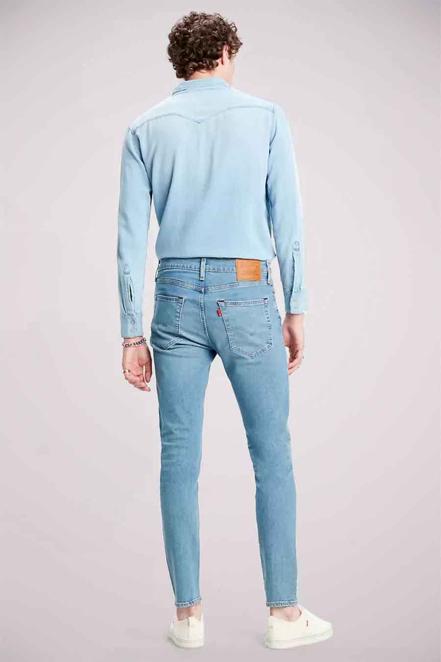 Lichtblauwe, taps toelopende jeans van Levi's, gedragen met een bijpassend blauw overhemd, van achteren gezien.
