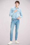 Slim-fit spijkerbroek in lichtblauw denim van Levi's, gedragen met een overhemd en witte schoenen.