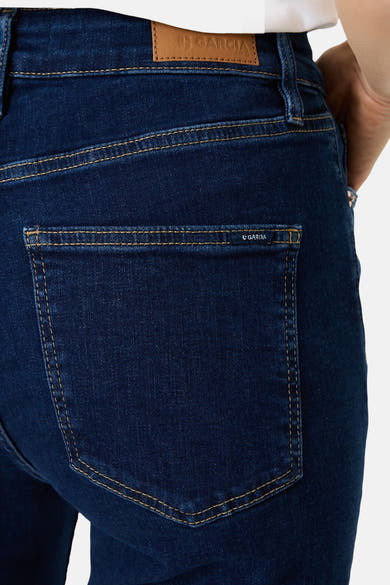 Dark blue flared jeans by Garcia with brown stitching and back pocket branding, close-up rear view