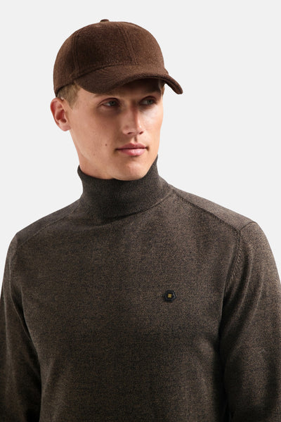 Pull à col roulé taupe de NO EXCESS, avec un petit logo noir et jaune sur le devant.