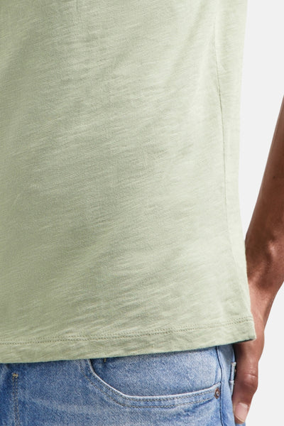 T-shirt à manches courtes vert de NO EXCESS, détail sur la poche de jean bleu clair.