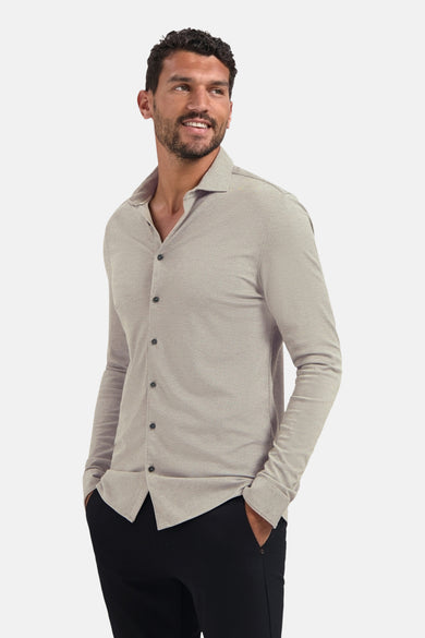 Chemise à manches longues beige de NO EXCESS, portée avec un pantalon noir uni.
