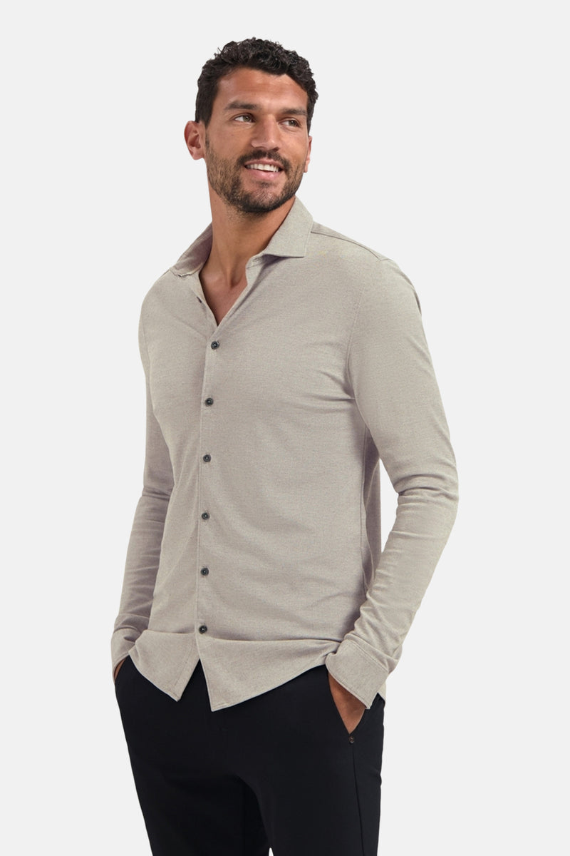 Chemise à manches longues beige de NO EXCESS, portée avec un pantalon noir uni.
